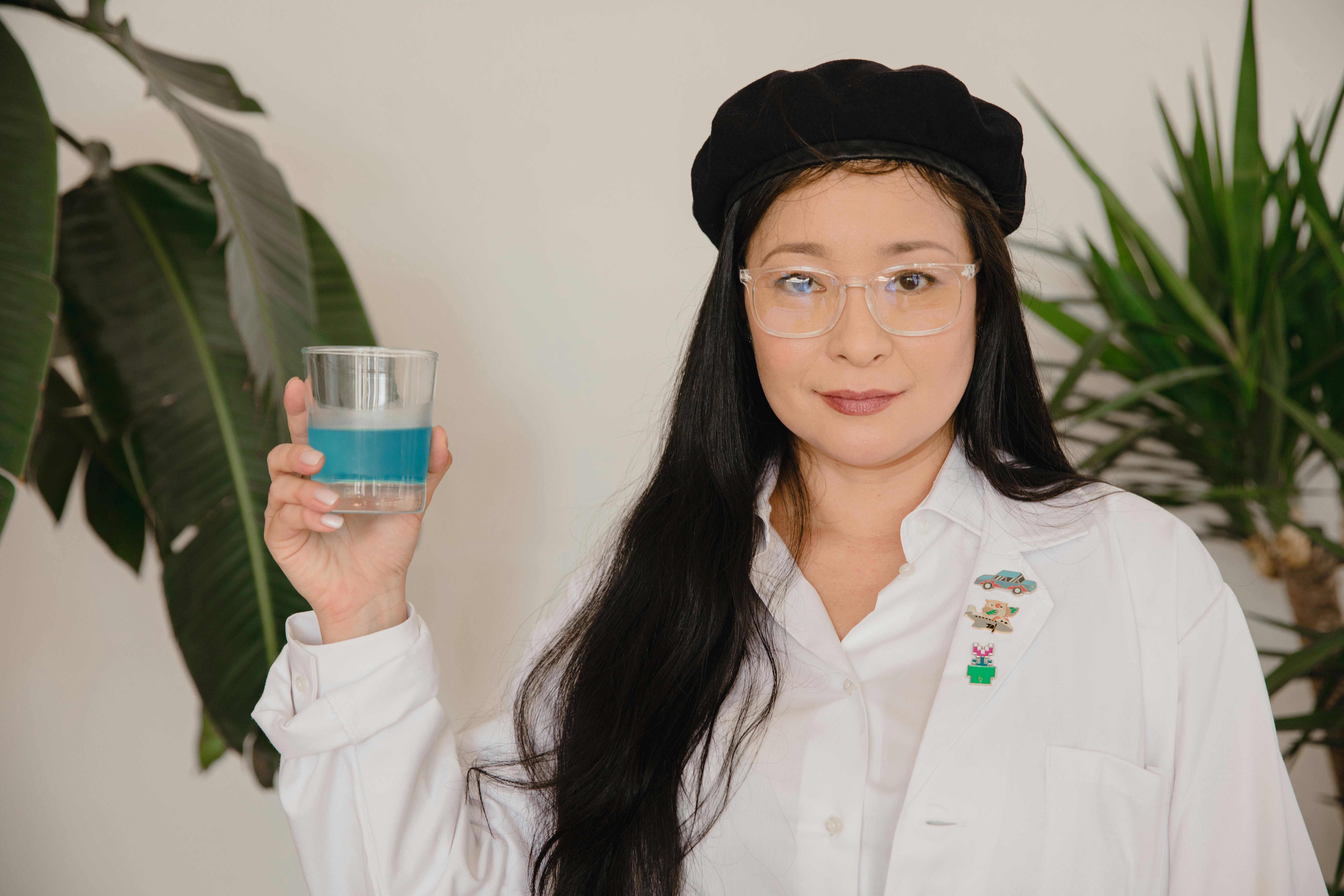 woman in white button up shirt holding blue and green plastic cup