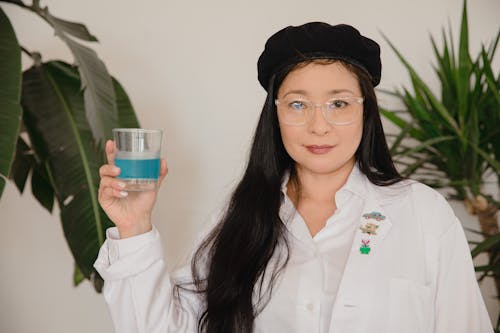 A Woman in a Beret Holding a Blue Beverage