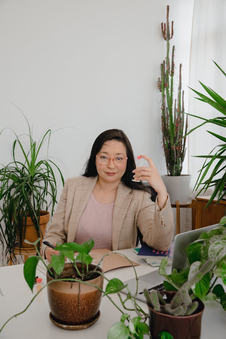 Woman In Beige Plaid Blazer Sitting And Holding A Plant Medicine