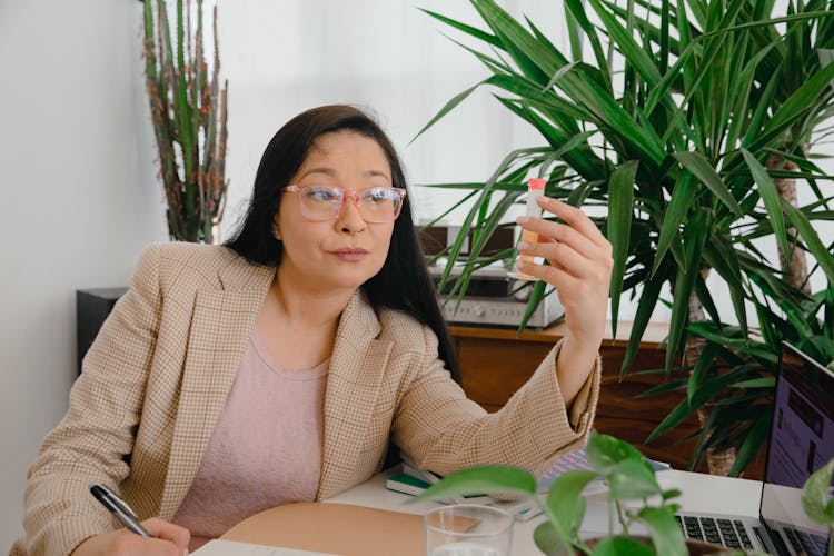 Woman In Beige Plaid Blazer Sitting And Holding A Plant Medicine