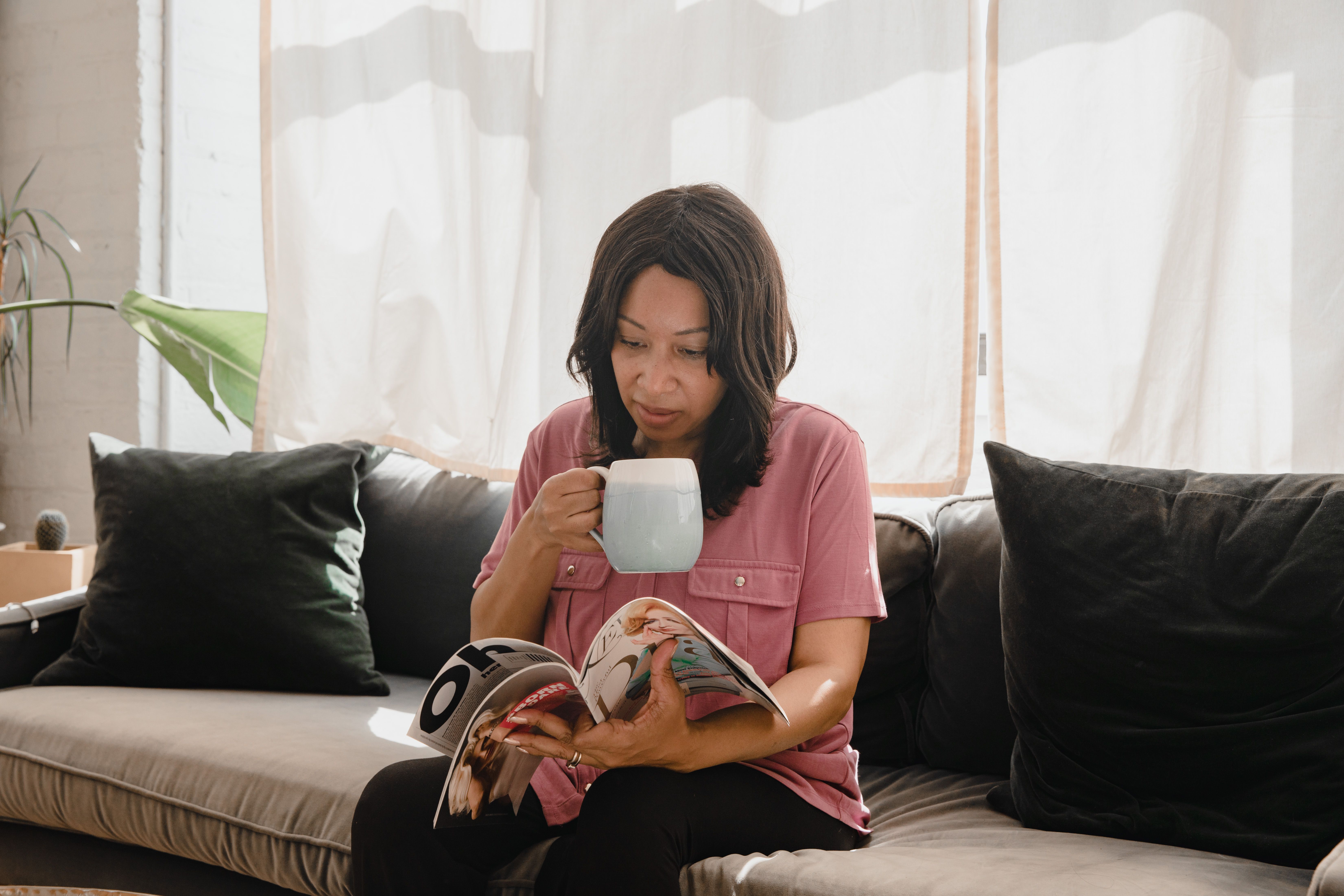 A woman enjoying a coffee while reading a magazine in a cozy living room setting.