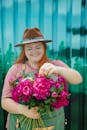 Woman in Pink Shirt Holding Pink Flowers