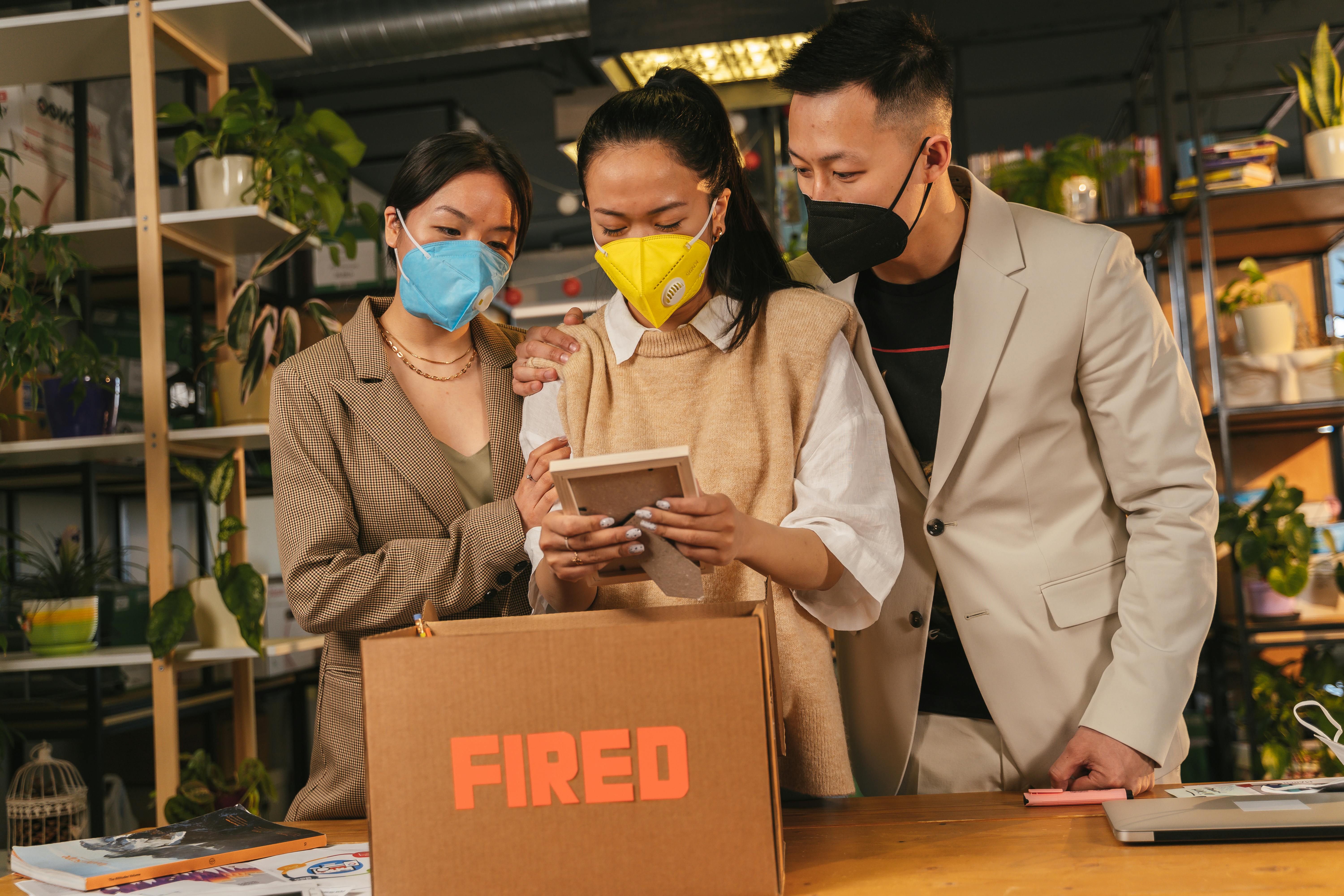 Colleagues support each other in an office, highlighting job loss during pandemic.