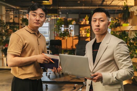 Two professionals collaborating in a stylish, plant-filled office setting.