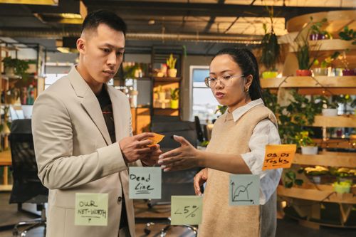 Free Two coworkers brainstorming with sticky notes in a modern office setting. Stock Photo