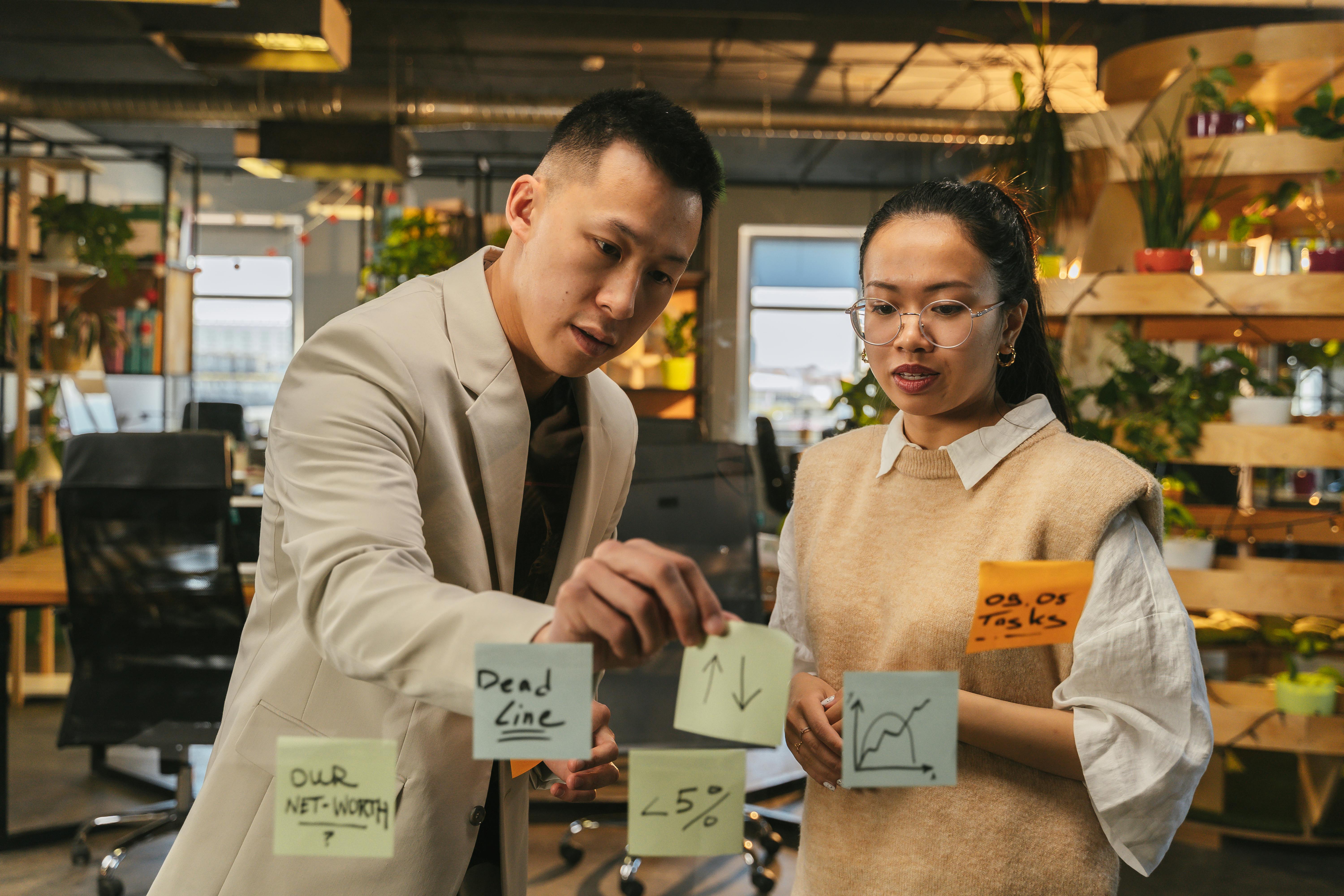 Two professionals engaging in strategic planning with sticky notes in a modern office setting.