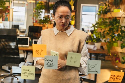 Free Focused woman strategizing with sticky notes in a modern office setting. Stock Photo