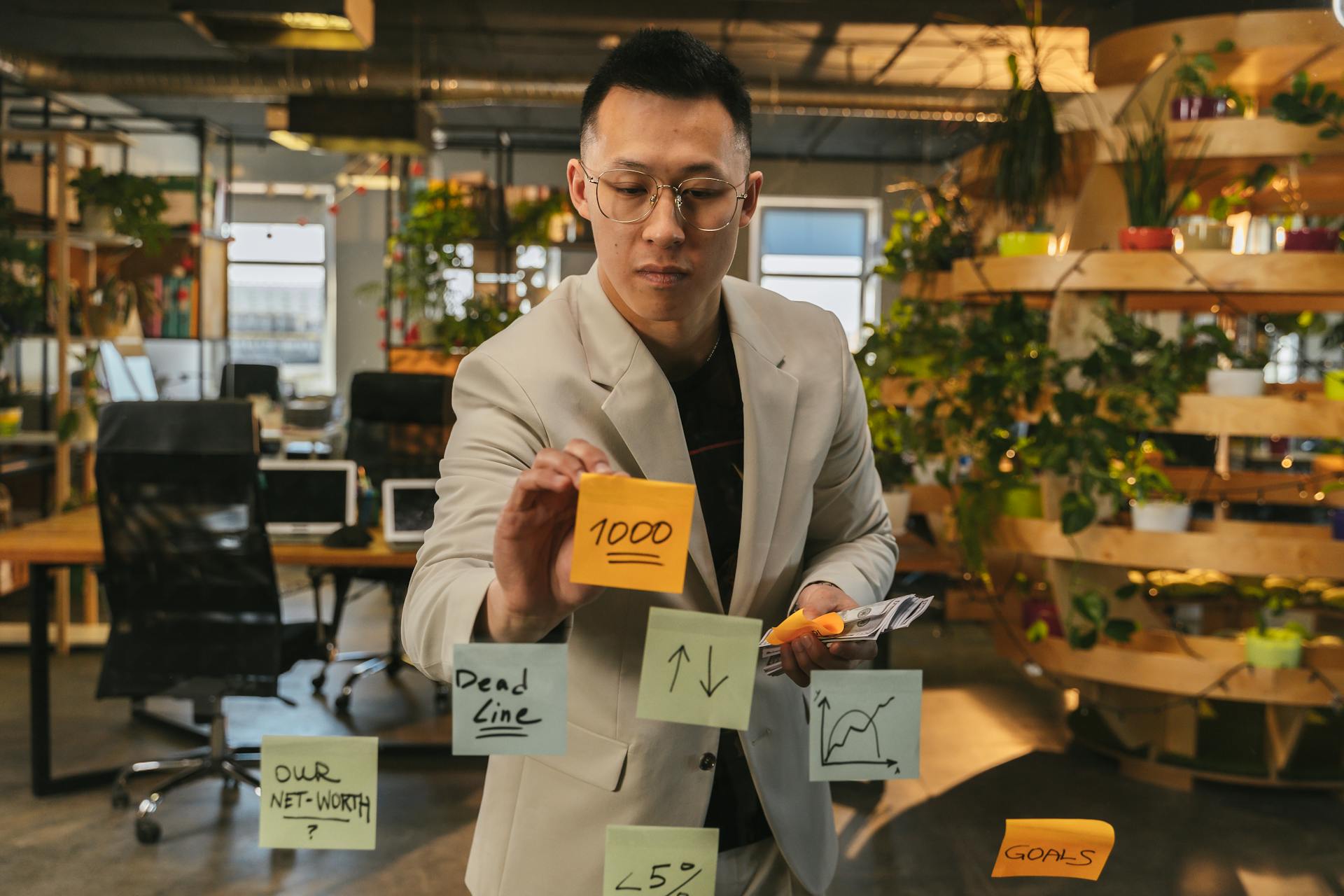 Focused businessman using sticky notes for planning in a green office.