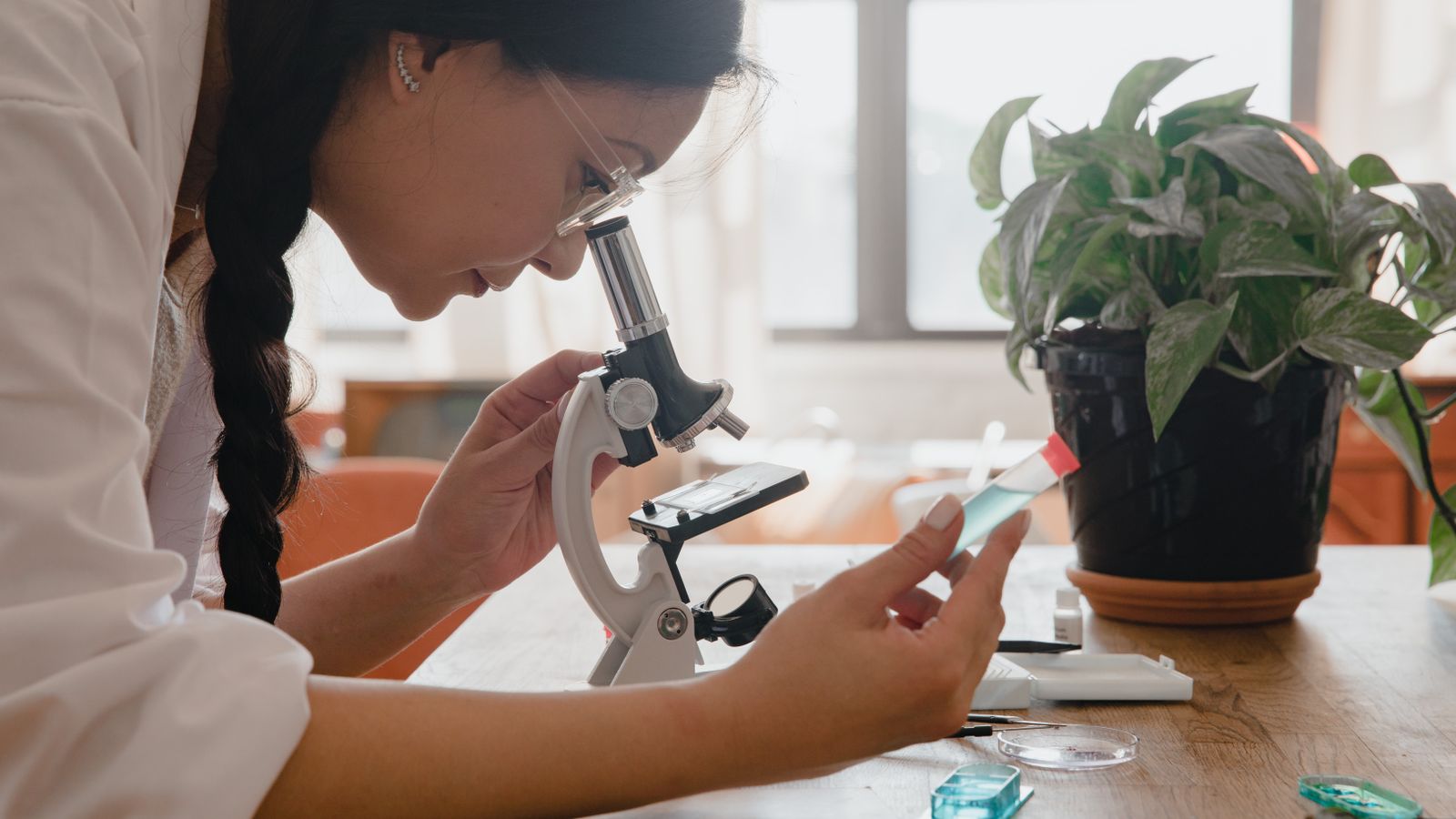 Woman examining sample under microscope in a lab, emphasizing research.