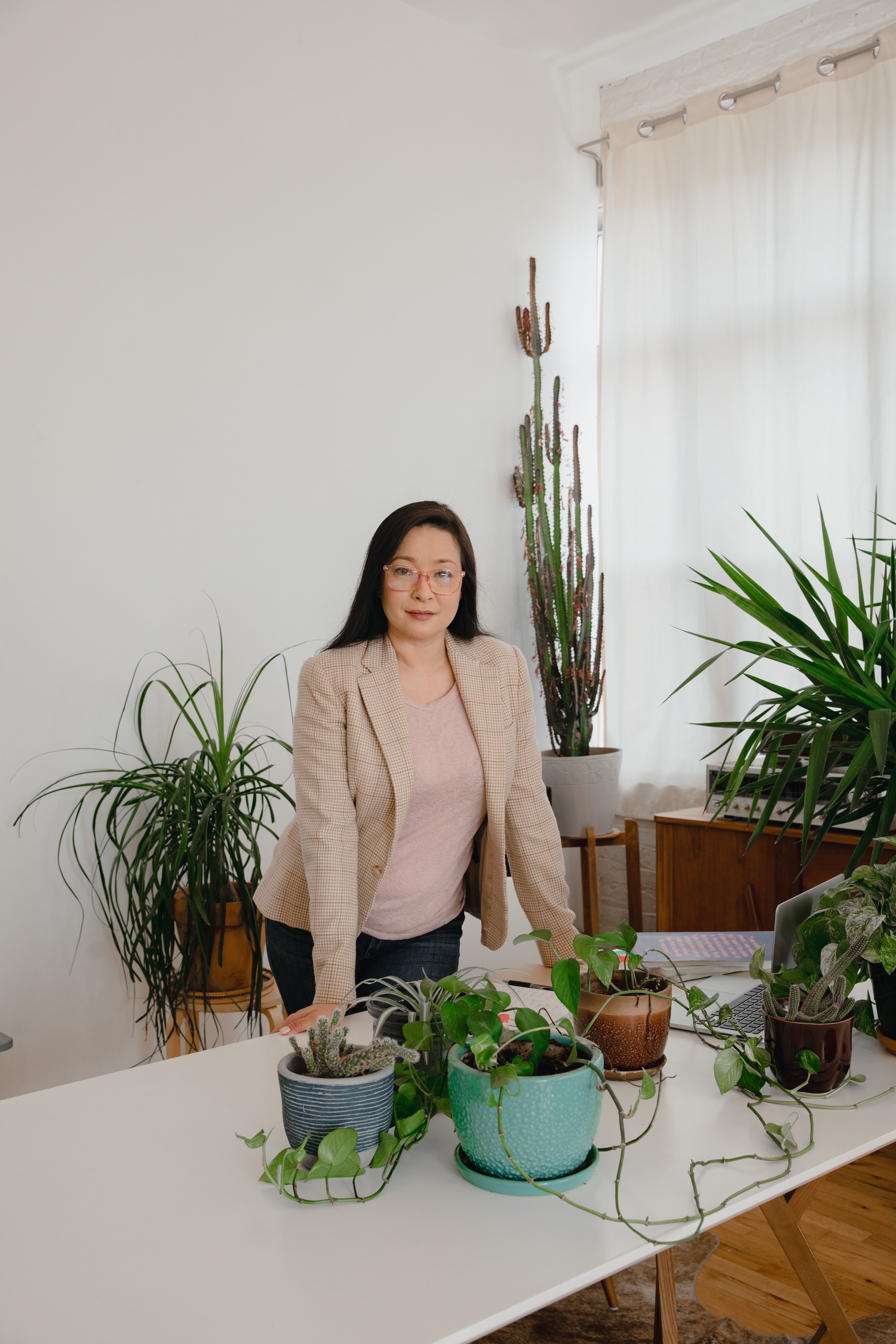 A Woman in Beige Blazer Standing Beside Green Plant · Free Stock Photo