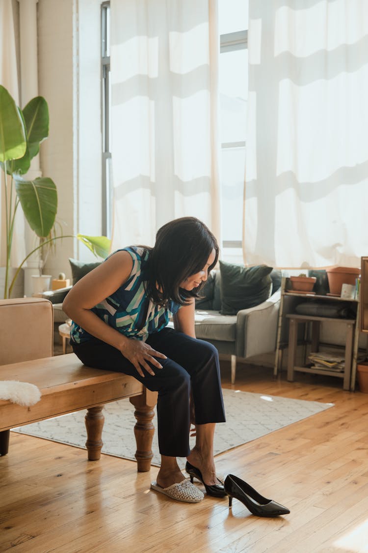 Woman In Sleeves Top And Pants Sitting And Putting On Shoes