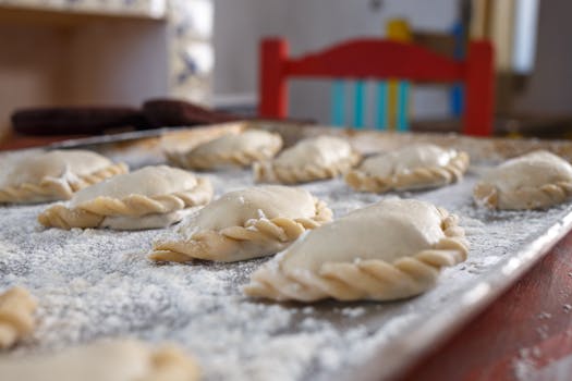 Close-up of freshly prepared empanadas on a flour-dusted tray, ready for baking.