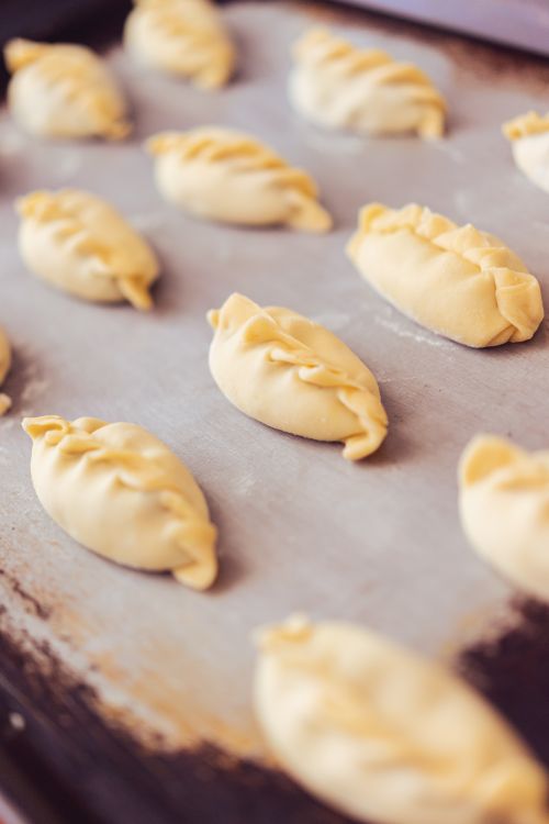Free Golden brown empanadas ready for baking, captured on a rustic tray. Stock Photo