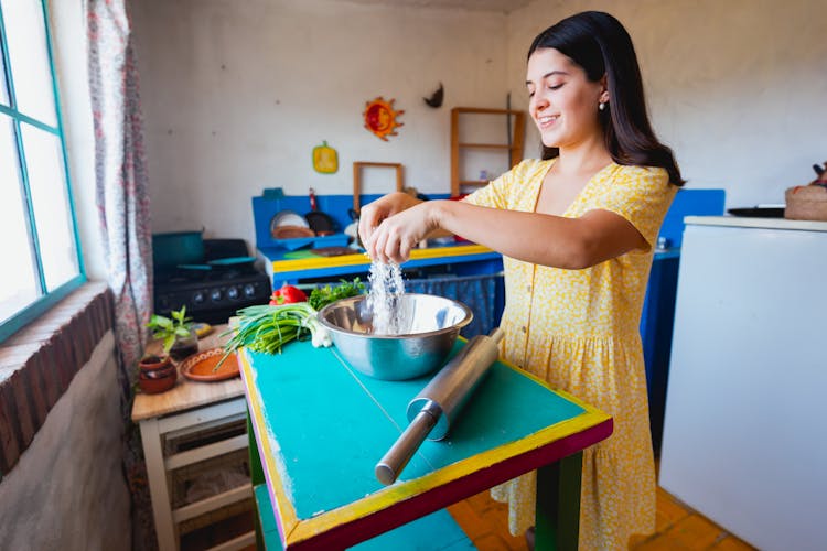 Woman In Yellow Dress Mixing Flour In Stainless Steel Bowl