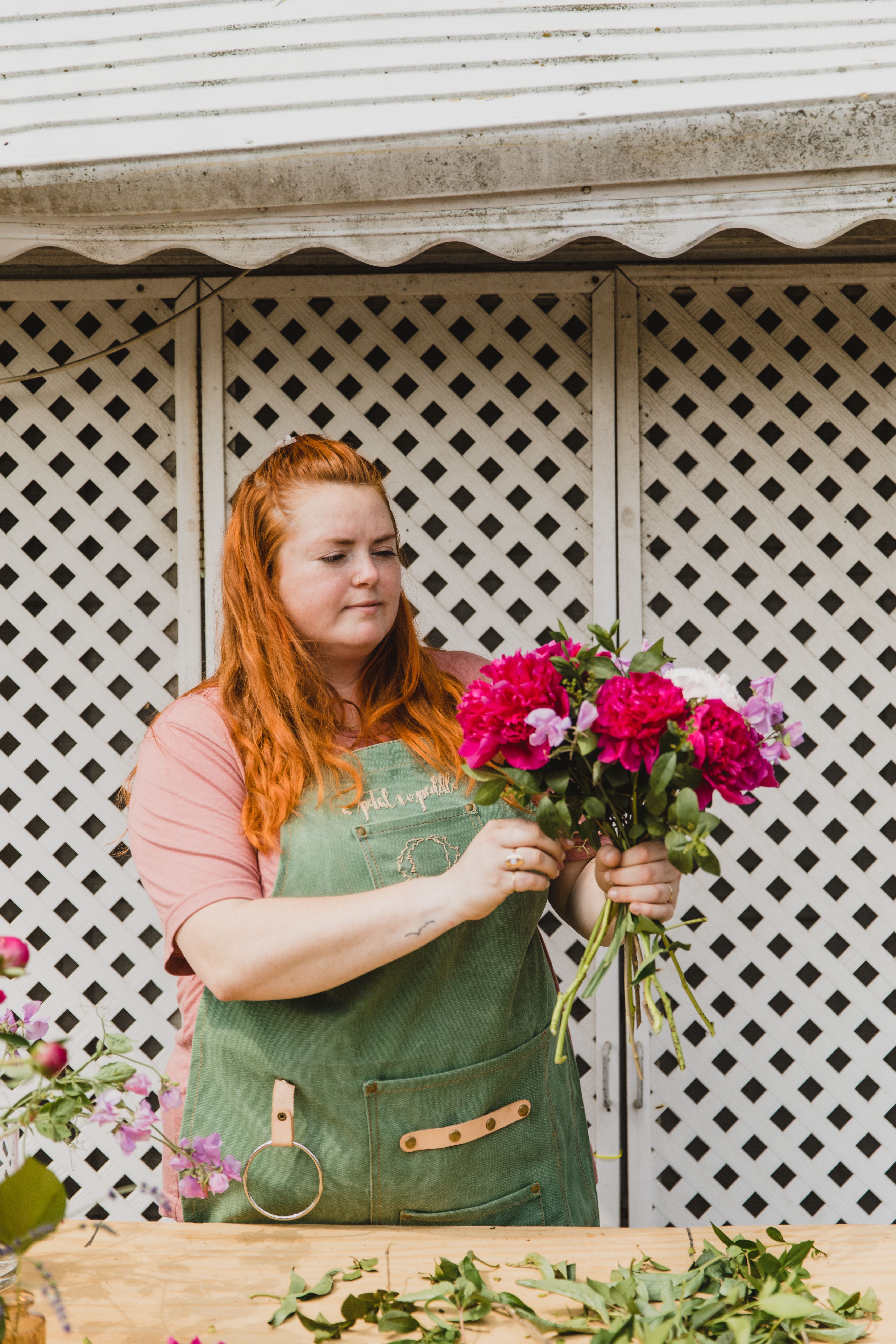 Florist in an apron holding an armful of fresh-cut flowers