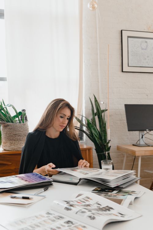 Free A woman in a black blazer reviews documents in a modern office setting. Stock Photo