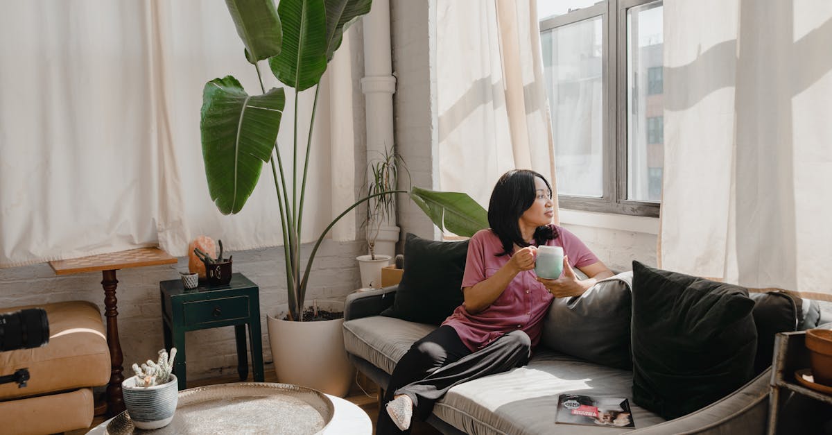 Woman Sitting On A Couch Looking Exhausted With Coffee Cup Nearby