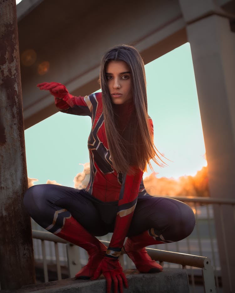 Model In Superhero Suit On Bridge Fence In Evening