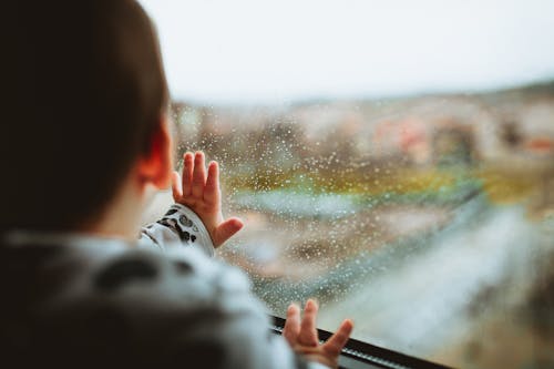 Free Selective Focus Photography of a Baby Looking Through The Window Stock Photo