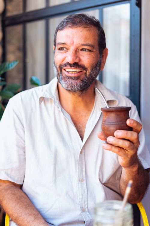 Free Smiling man holding a wooden cup of yerba mate, showcasing cultural tradition. Stock Photo