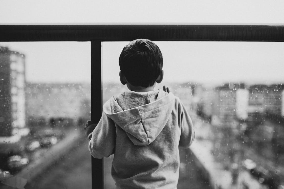 Free Backview of Sad Child waiting on a Glass Window Stock Photo
