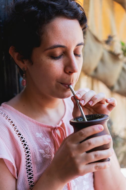 Woman in Pink Shirt Drinking on Black Ceramic Mug