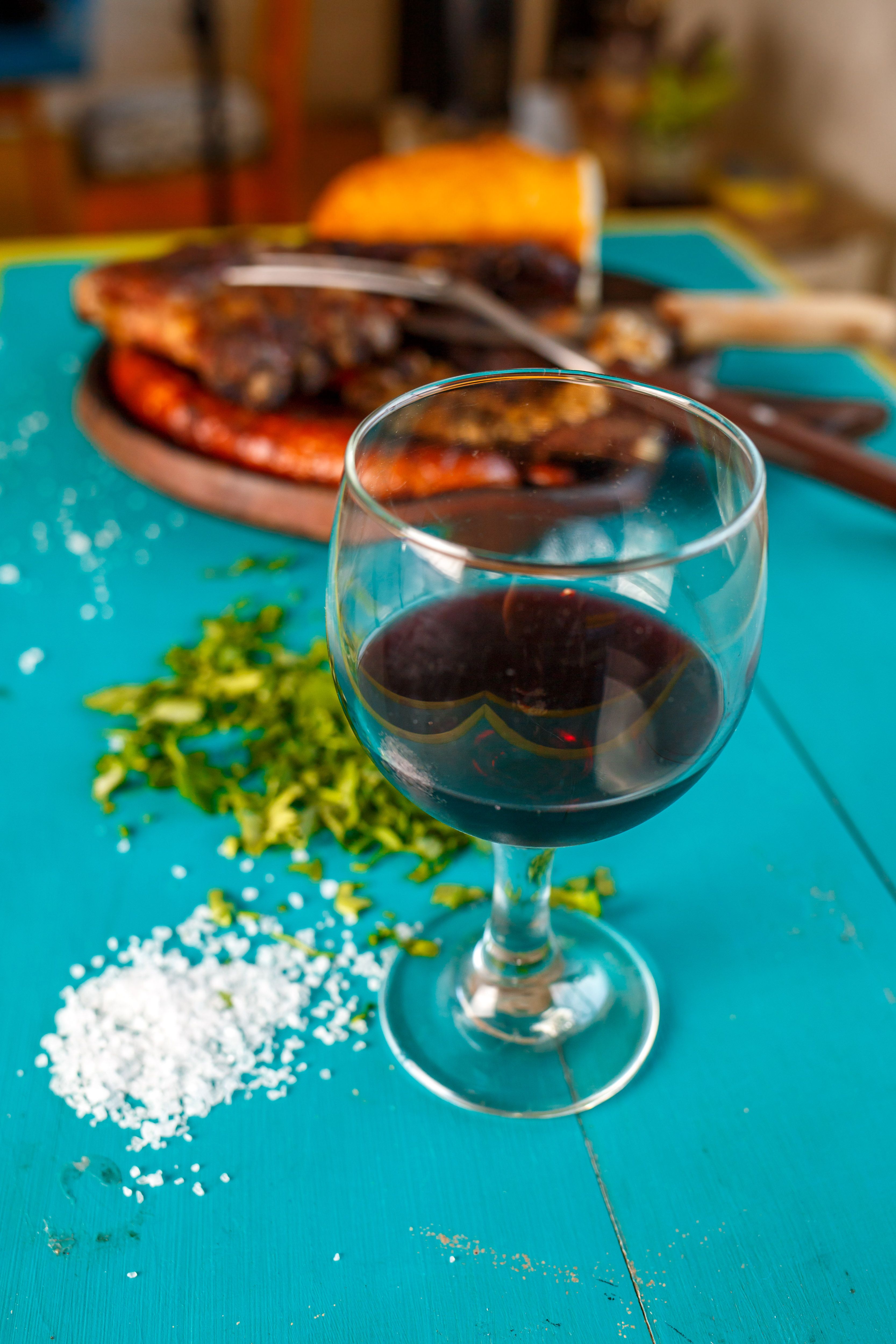 Copa de vino tinto junto a un asado argentino