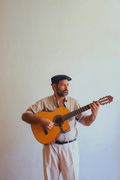Free A Man in Beige Button-Up Shirt Playing an Acoustic Guitar Stock Photo