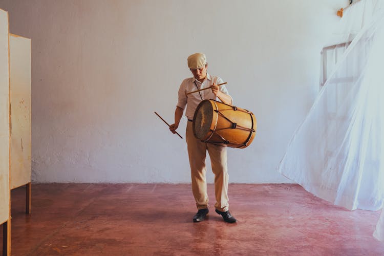 A Musician Carrying Bombo Drum And Drumsticks