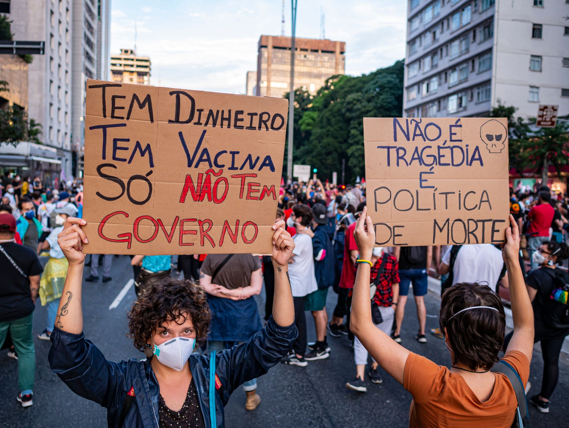 Protesters hold signs criticizing government during a rally in São Paulo, Brazil, advocating for human rights and democracy.