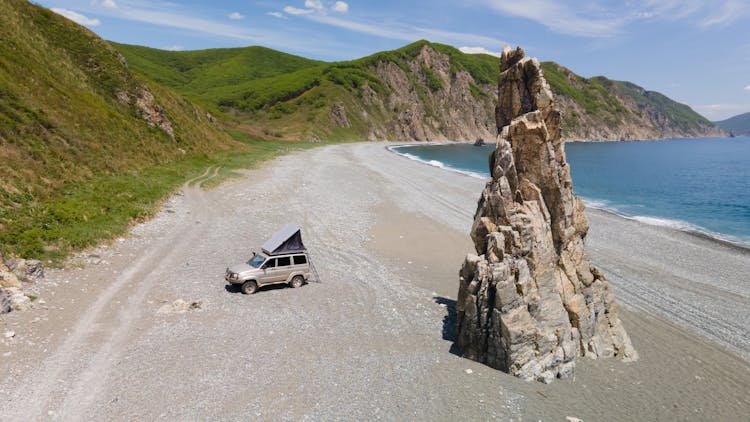 An SUV Parked On The Shore Of A Beach