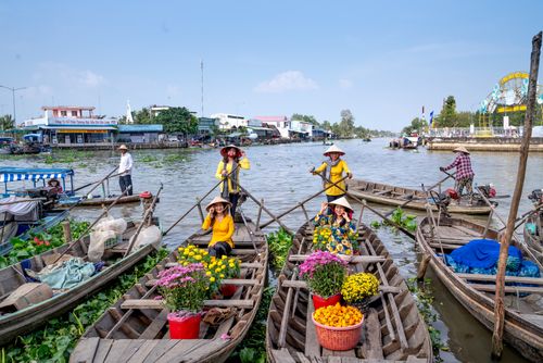 Free Colorful floating market in Vietnam featuring women on boats selling flowers and goods. Stock Photo