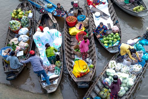 Free Colorful floating market scene with vendors selling fruits and goods from boats on a calm river. Stock Photo
