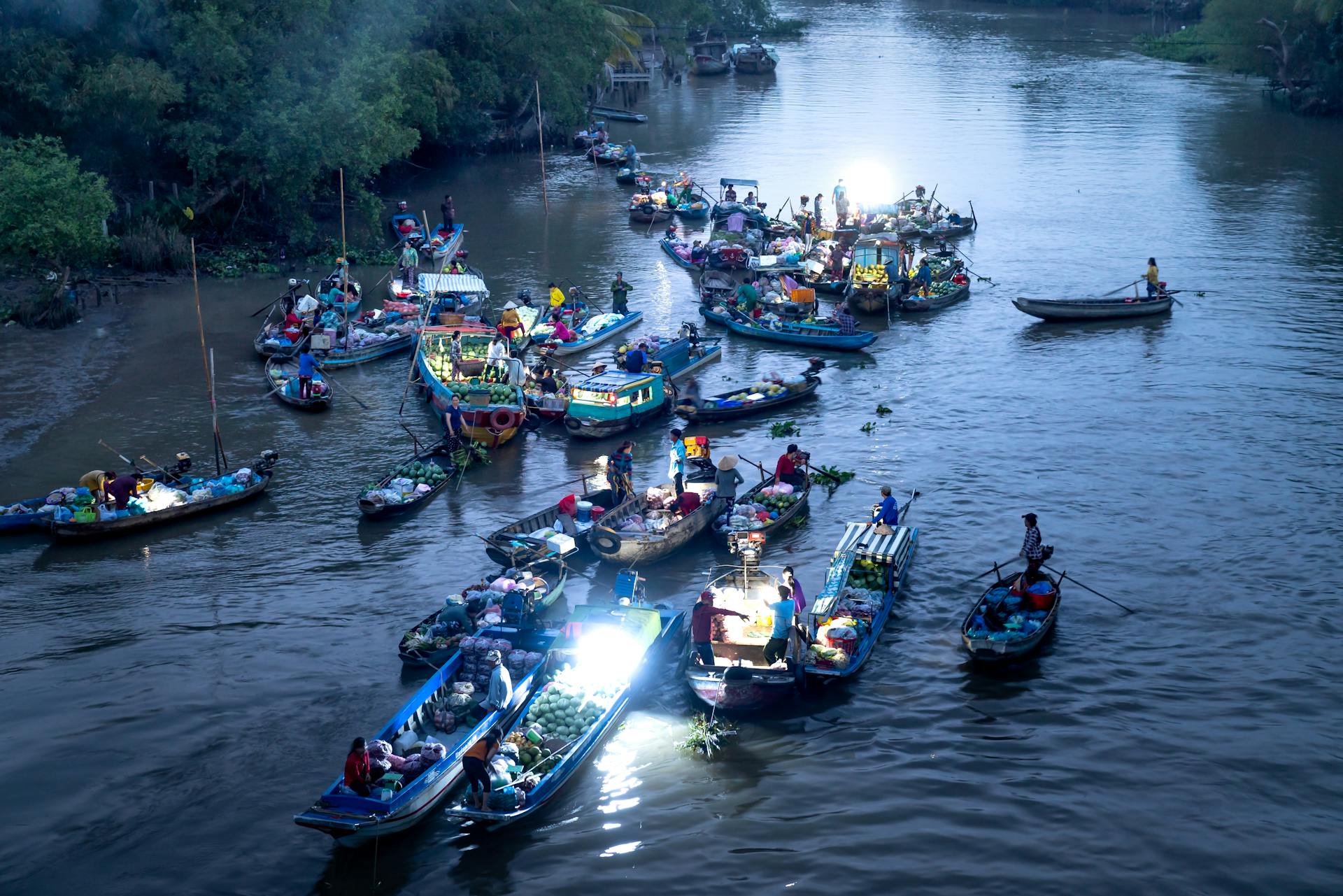 Aerial view of a floating market with boats illuminated on a Vietnamese river at night.