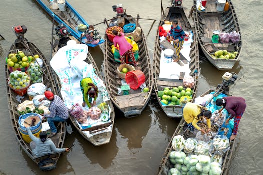 Colorful boats at a busy floating market with people trading tropical fruits.