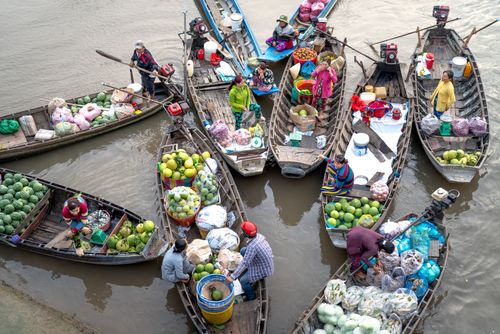 Free Colorful floating market showcasing boats with fruits and vegetables being sold by merchants. Stock Photo