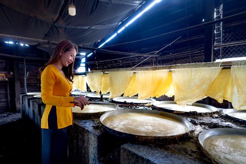 Free Woman preparing traditional rice paper in a Vietnamese workshop. Stock Photo