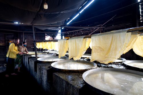 Free Women preparing rice paper in a traditional Vietnamese indoor setting. Stock Photo