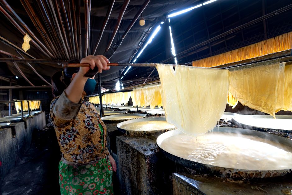 Asian woman making traditional rice paper in Vietnam indoors.