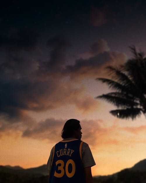 Man Wearing a Jersey Posing Under Dark Clouds