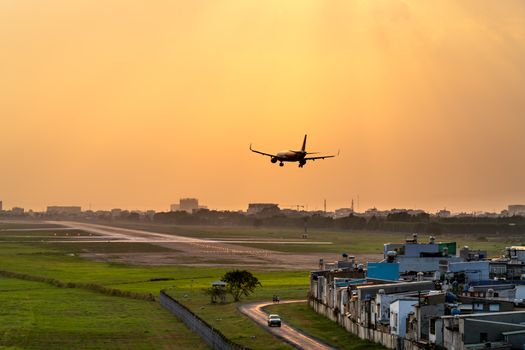 A scenic view of an airplane landing on a runway at sunset, capturing a dramatic sky.