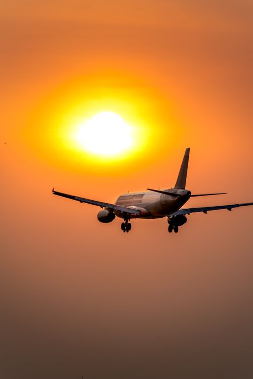Free Airplane soaring towards a golden sunset sky, creating a dramatic silhouette. Stock Photo