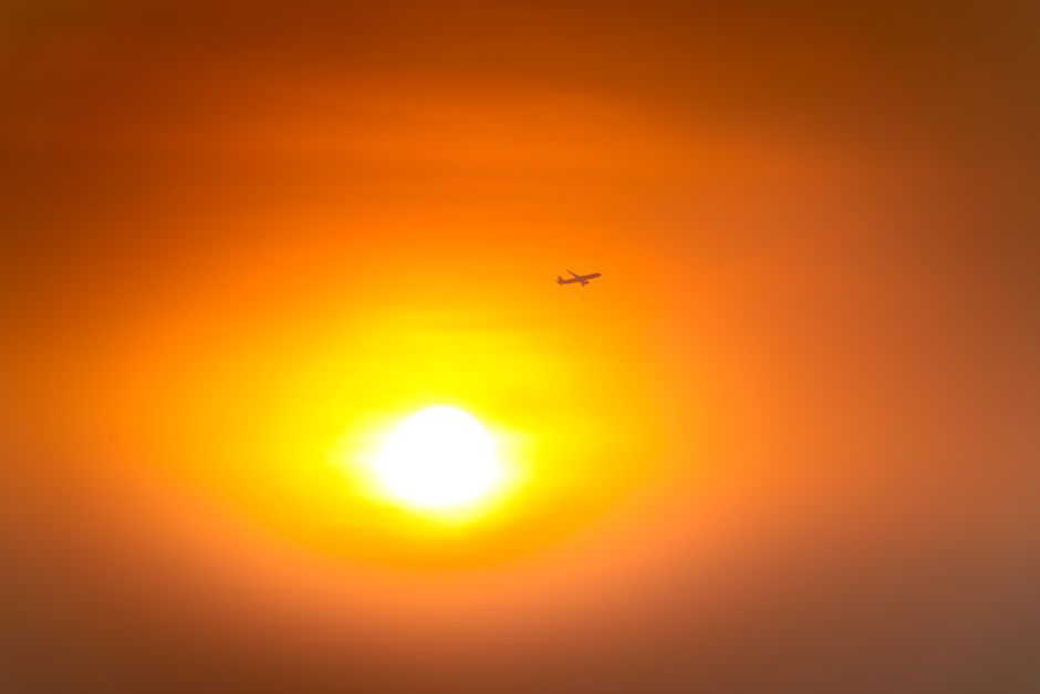 A silhouette of an airplane flying against a warm, vibrant sunset sky creating a dramatic view.