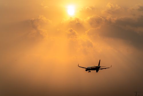 Free Airplane flying against a golden sunset sky, creating an evocative silhouette. Stock Photo