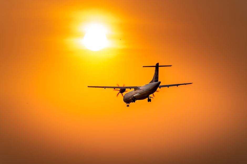 A dramatic silhouette of an airplane flying against a vibrant sunset sky, capturing a sense of adventure and travel.