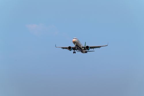 Free A low angle shot of a commercial airplane flying against a clear blue sky, emphasizing air travel. Stock Photo