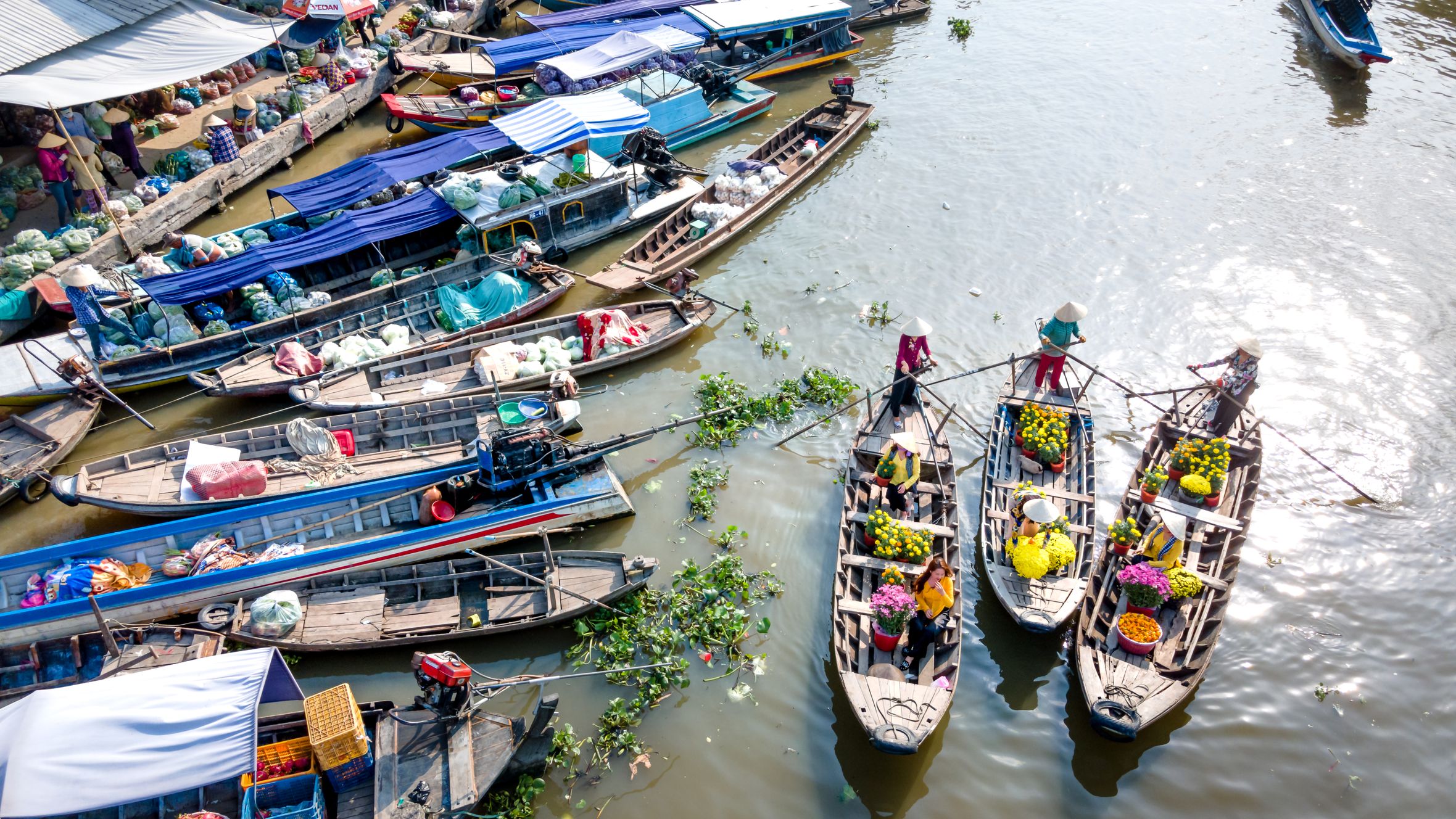 Vibrant river market with boats laden with fruits and vegetables, showcasing local culture.