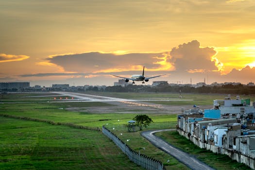 Airplane landing on runway with dramatic sunset sky in background, capturing the golden hour.