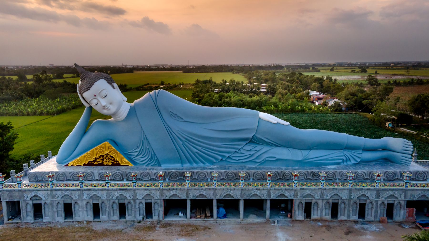 Discover the tranquility of the giant reclining Buddha statue at Som Rong Pagoda, captured at sunset.
