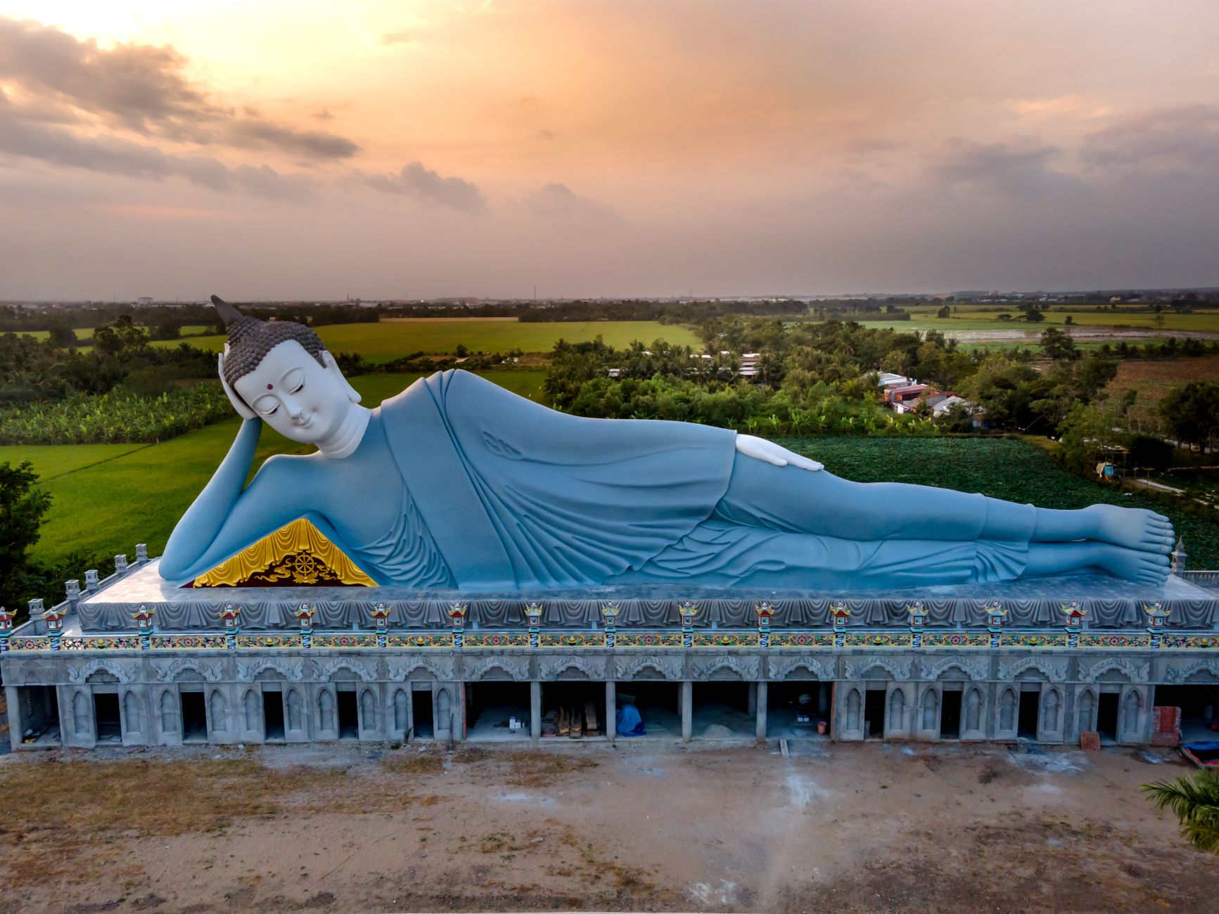 Discover the tranquility of the giant reclining Buddha statue at Som Rong Pagoda, captured at sunset.